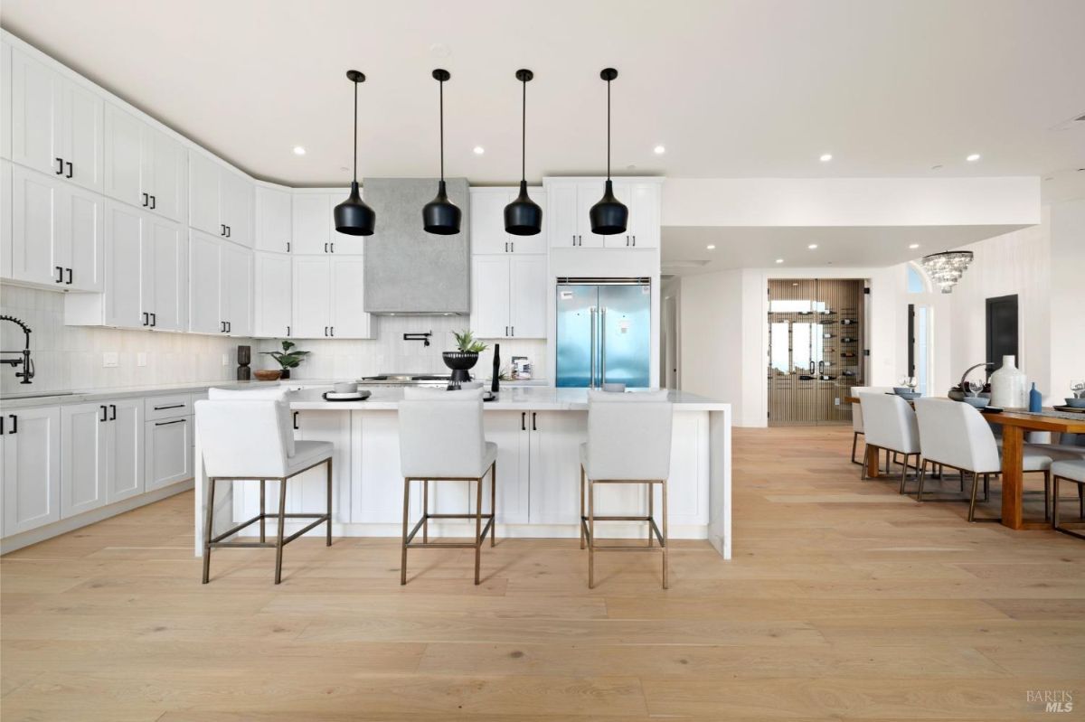 Spacious kitchen with a white marble island, black pendant lights, and stainless steel appliances.