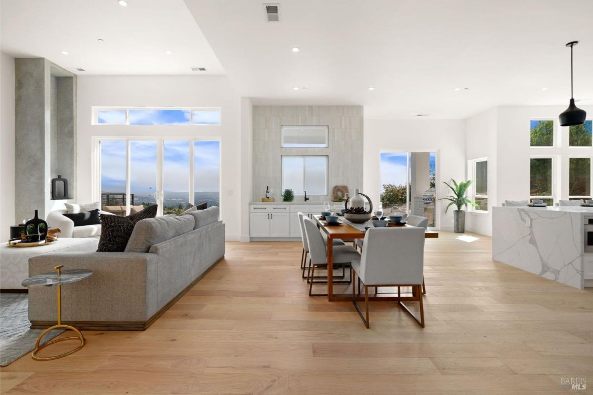 Modern living room with a gray sofa, large windows, and a view of the outdoors.