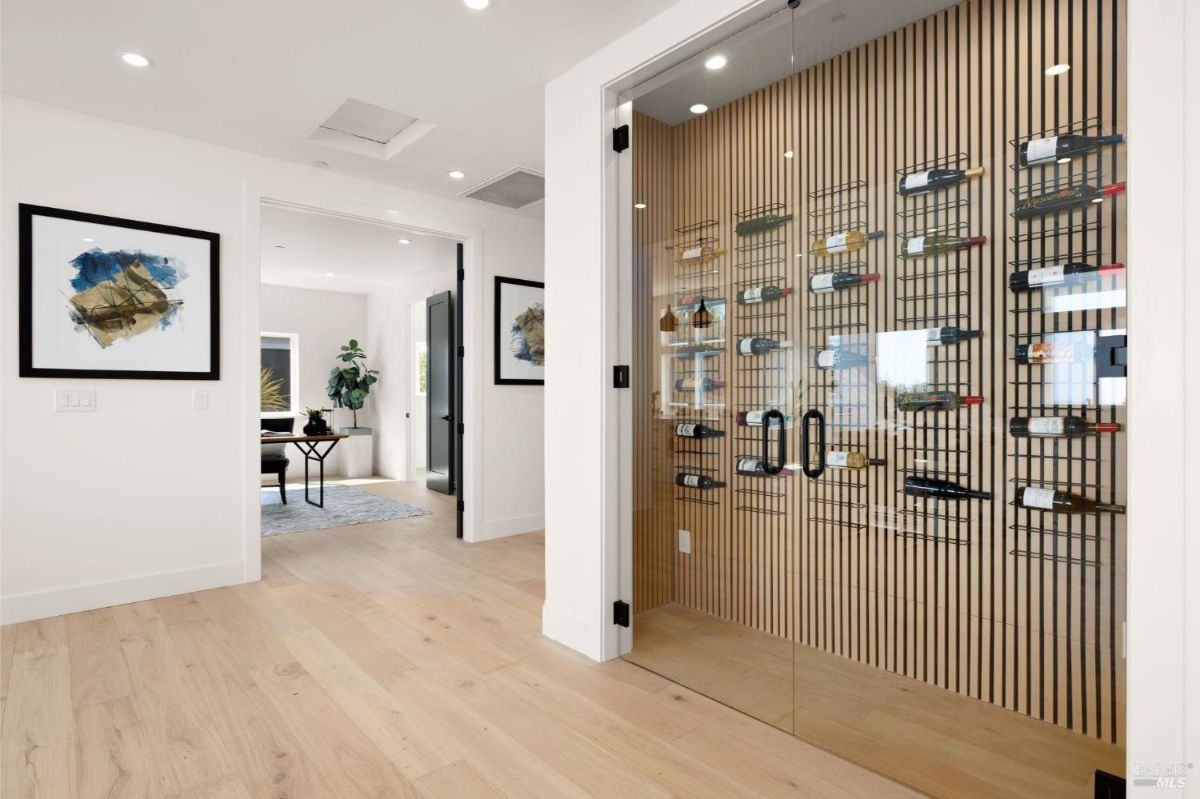 Hallway with a glass-enclosed wine storage display and wooden flooring.