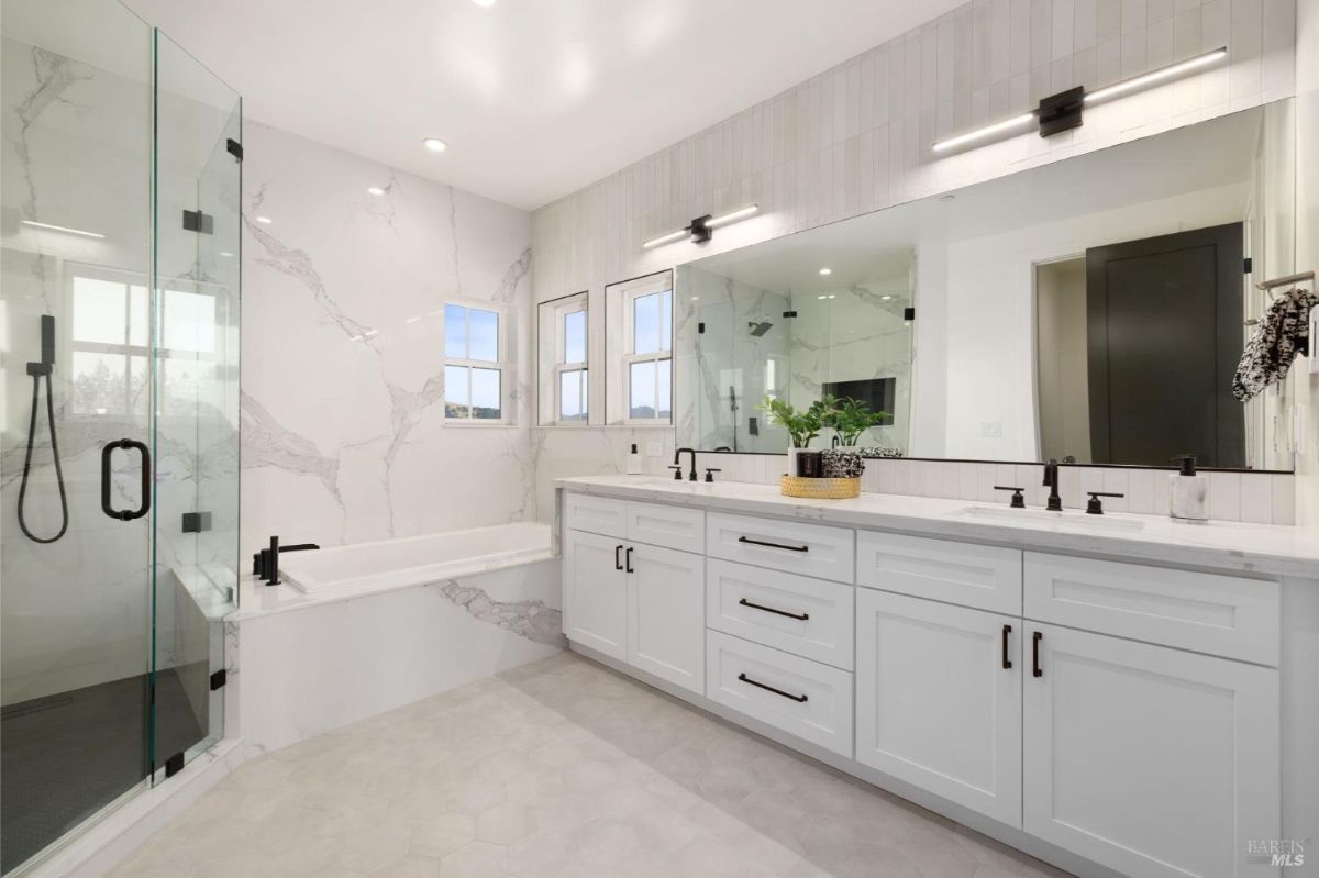 Master bathroom with a glass shower, a bathtub, and dual vanity sinks.