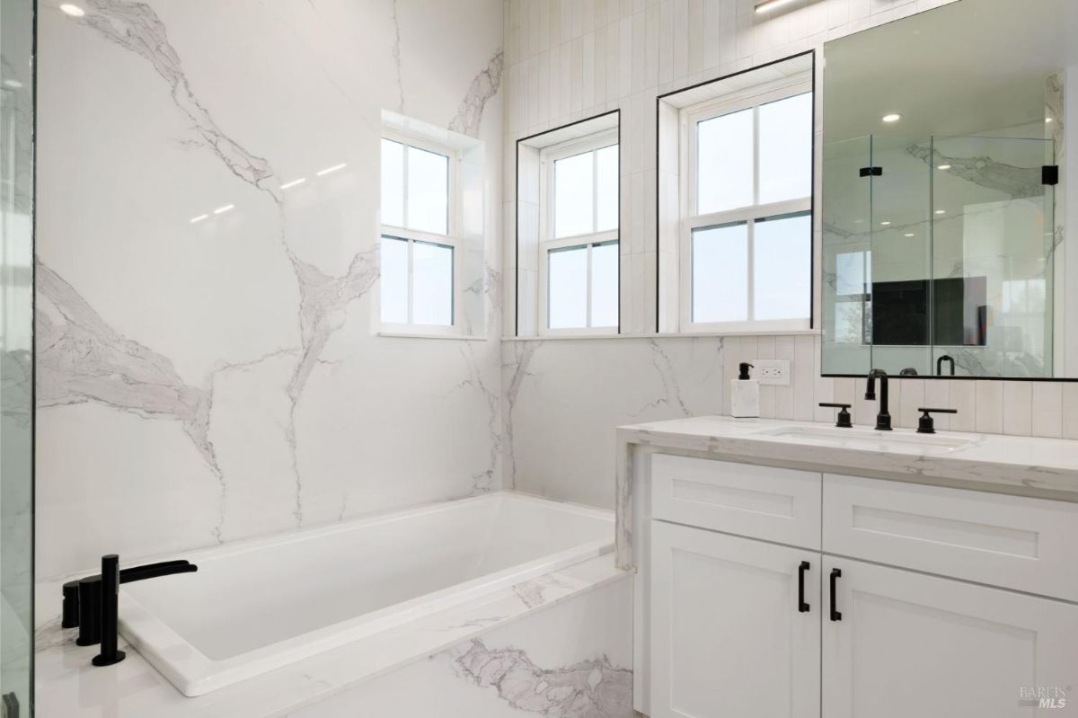 Kitchen with white cabinetry, a large marble island, and pendant lighting.