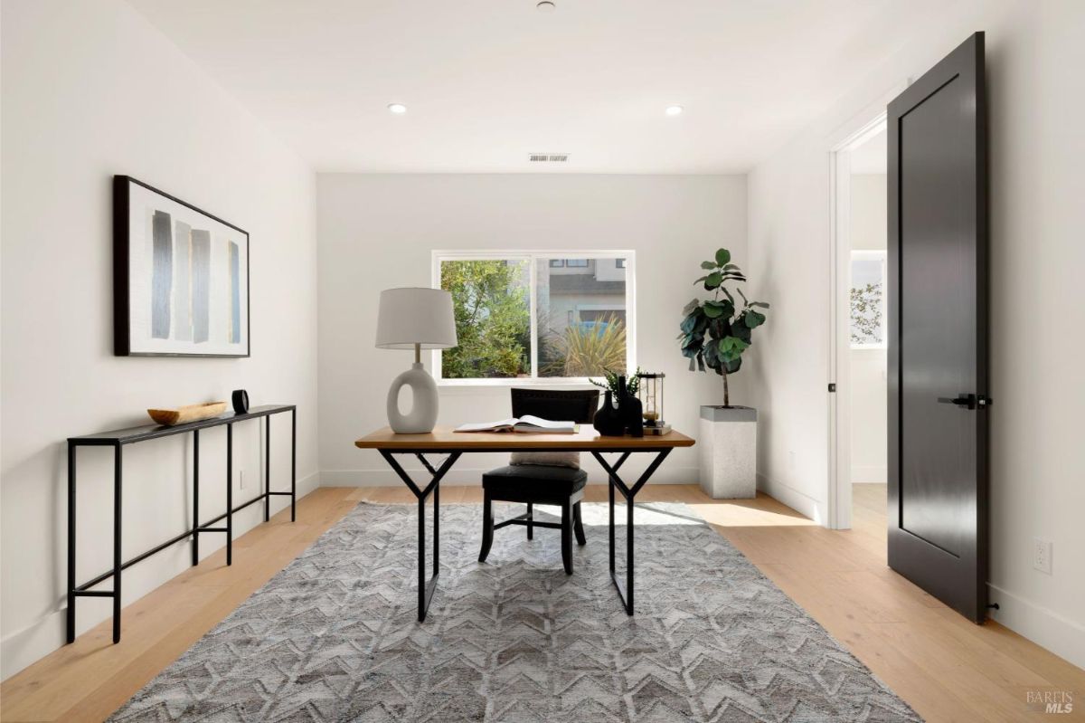 Home office with a wooden desk, large window, and minimal decor.