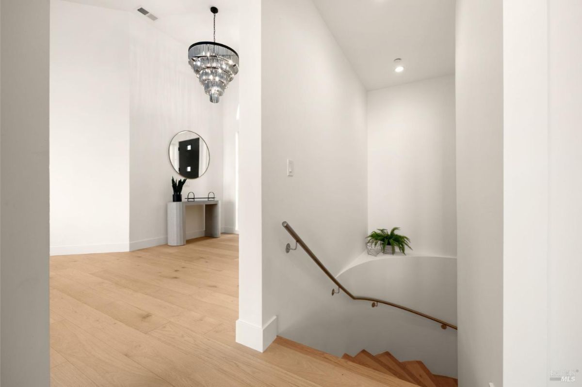 Staircase with wooden steps, a chandelier, and a minimalist decor.