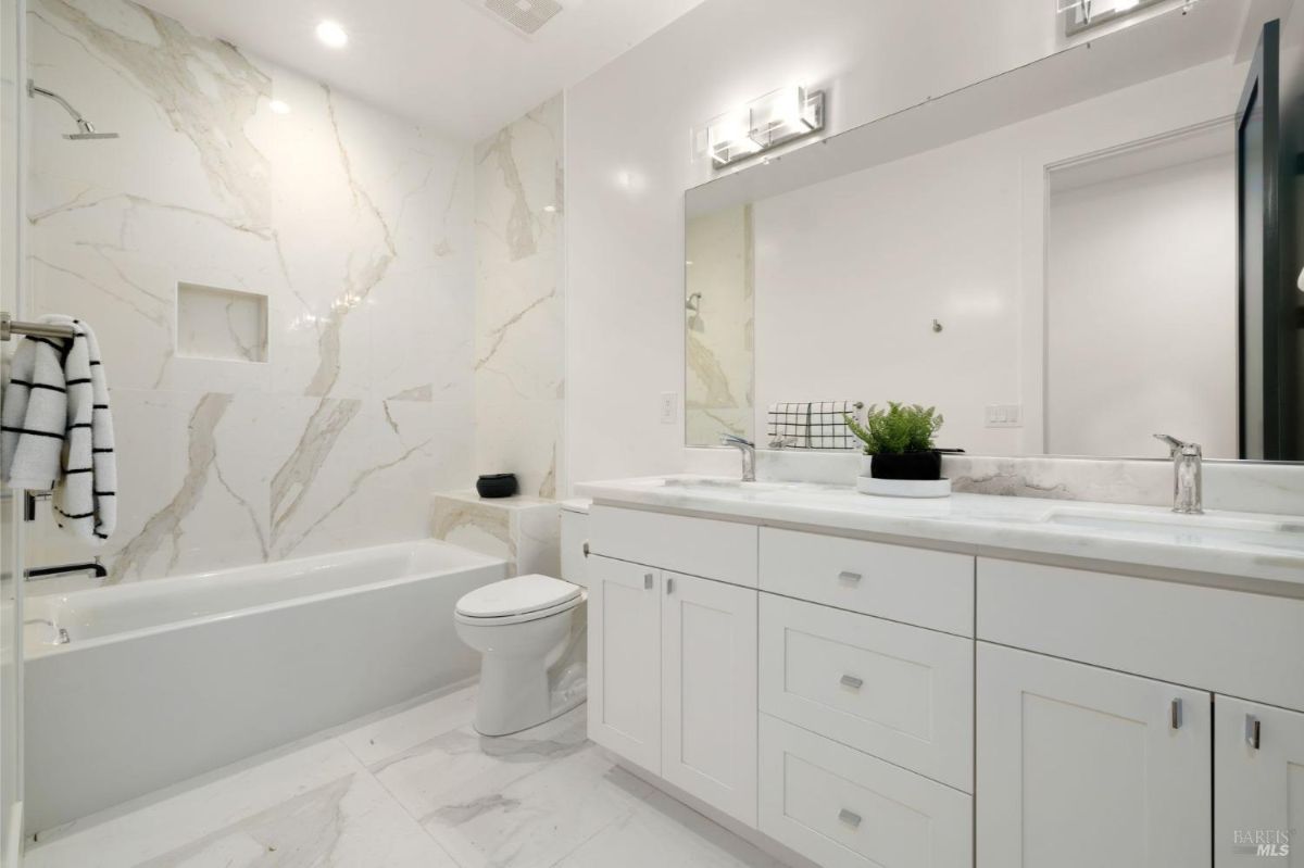 Guest bathroom with a bathtub, marble tiles, and a single vanity sink.