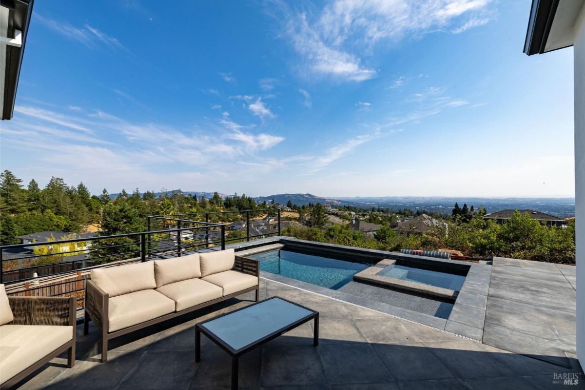 View of an outdoor seating area beside a pool overlooking a residential neighborhood.