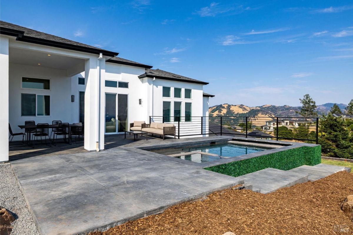 Outdoor patio with a pool, seating area, and mountain views.