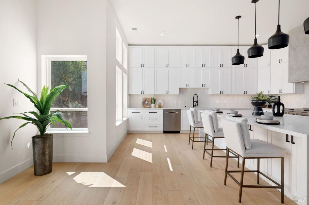 Bright kitchen with white cabinets, a large island, and modern pendant lighting.