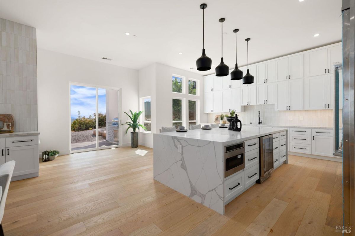 Kitchen and dining layout with sleek white cabinetry, high ceilings, and bar seating.